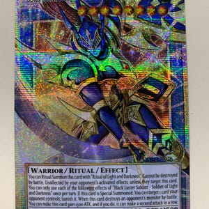 May include: A holographic trading card featuring the "Black Luster Soldier - Soldier of Light and Darkness." The card has a warrior figure in blue and gold armor, with text describing its abilities. The card's ATK is 3000, and DEF is 2500.