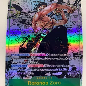 Peut inclure: Carte à collectionner holographique représentant Roronoa Zoro de l'équipage du Chapeau de Paille. La carte a une bordure verte et montre le personnage en action avec des épées. Le texte comprend "I WILL NEVER LO AG" et "9000".