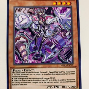 Può includere: Una carta da gioco di scambio viola e bianca con un personaggio dei cartoni animati con un cappello rosa e bianco, che tiene una grande macchina viola e bianca. La carta è intitolata "Vanquish Soul Dr. Mad Love" e ha uno sfondo scuro. La carta è una carta "Fiend/Effect" con un potere d'attacco di 1200 e un potere di difesa di 2000.