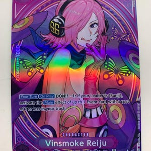 May include: A collectible trading card featuring Vinsmoke Reiju from the One Piece series. The card has a purple and pink colour scheme with holographic accents. The character is depicted with pink hair, headphones, and a playful expression. The card includes text and a power level of 5000.