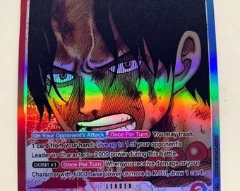 Puede incluir: Carta coleccionable holográfica con Portgas D. Ace de los Whitebeard Pirates. La tarjeta muestra una ilustración detallada del rostro de Ace con una expresión decidida, texto del juego y una potencia de 6000.