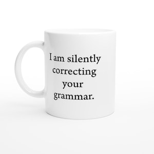 May include: White ceramic coffee mug with black text that reads "I am silently correcting your grammar."