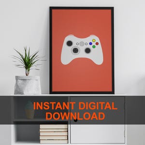 Puede incluir: Impresión enmarcada con un mando de videojuegos blanco sobre un fondo naranja. El mando tiene botones negros y de colores. El texto "INSTANT DIGITAL DOWNLOAD" se muestra en naranja en la parte inferior de la imagen.
