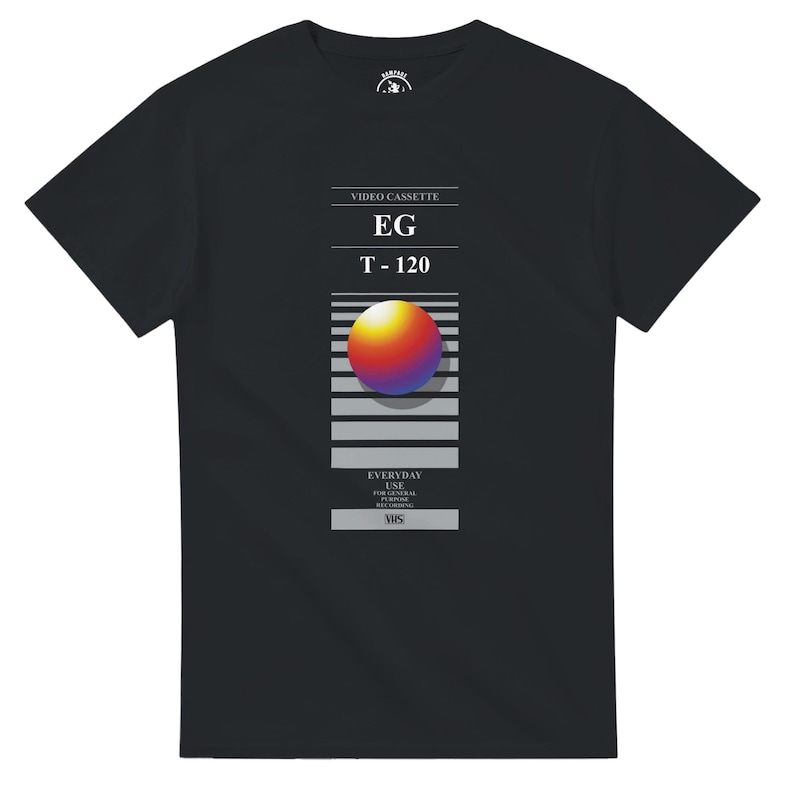 May include: Black t-shirt with a retro VHS tape design. The graphic includes the text "VIDEO CASSETTE", "EG", "T-120", and "EVERYDAY USE". A colourful sphere is centered on the tape design.
