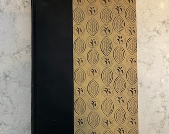 May include: A black hardcover book with a gold spine and a decorative pattern on the cover. The pattern features stylized leaves and flowers in a repeating design.