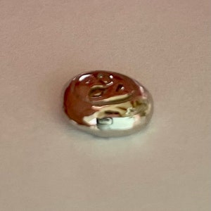 以下が含まれることがあります： 上面が盛り上がった刻印のある、小さく丸い銀色の金属のインゴット