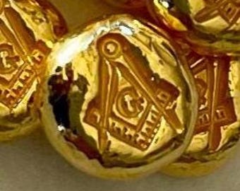 May include: Close-up of several gold-colored buttons with a Masonic symbol engraved on each. The symbol includes a compass, square, and the letter "G". The buttons have a shiny, reflective surface.