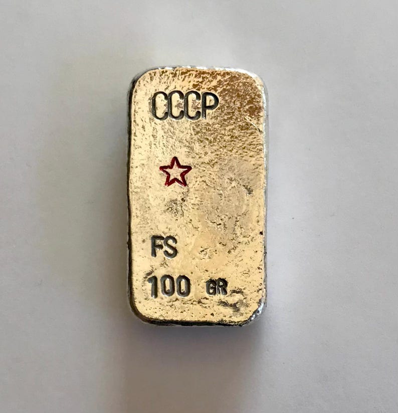 May include: A silver bar with the inscription "CCCP" and a red star. The bar also has the inscription "FS 100 GR".