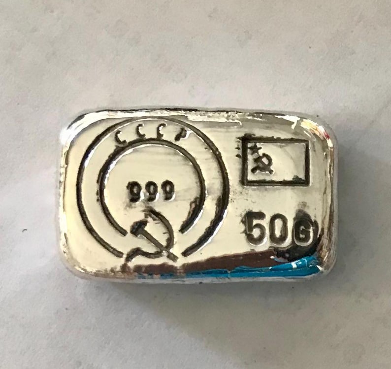 May include: A silver bar with the inscription "CCCP 999" and a hammer and sickle symbol. The bar also has the inscription "50g" and a small square with a star inside.