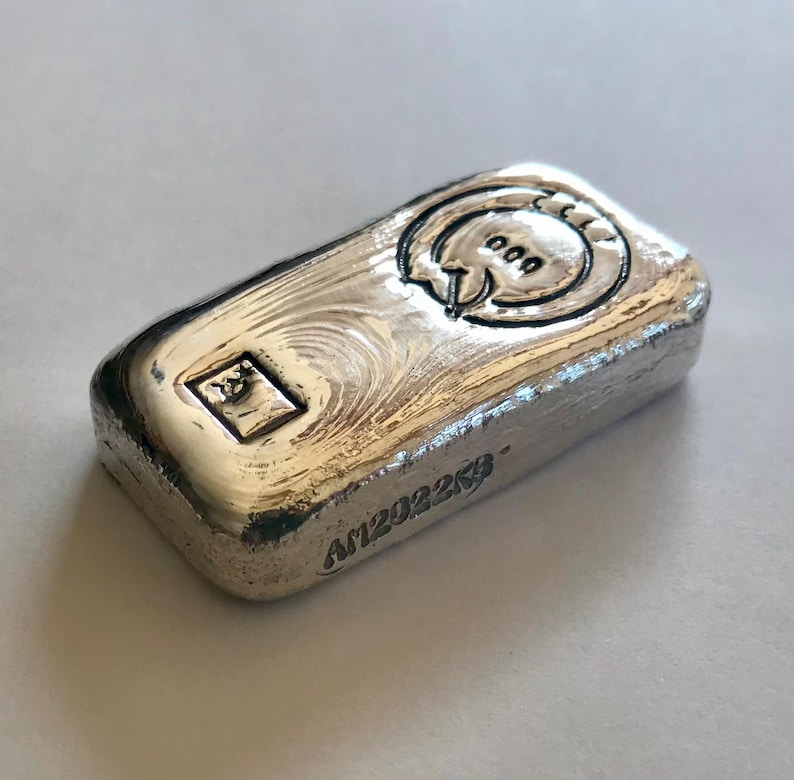 May include: A silver bar with a stylized logo and the text "A1202225".