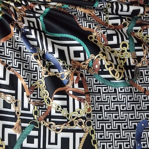 May include: Black fabric with a white, black, and gold chain pattern. The fabric also has a green rope pattern and brown leather straps.