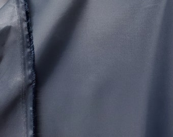 May include: Close-up of a dark gray fabric with a subtle texture. The fabric has a raw edge and is sewn along one side.