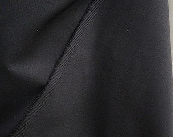 May include: Close-up of black fabric with a textured surface. The fabric is folded over itself, creating a diagonal seam.