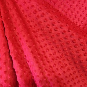 K&ouml;nnte beinhalten: Roter Stoff mit einem strukturierten, gepunkteten Muster. Der Stoff ist weich und pl&uuml;schig.
