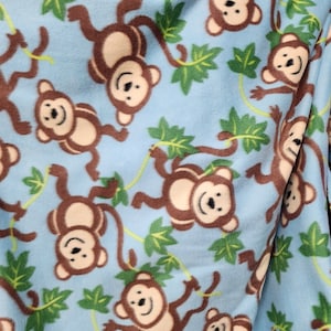 May include: A blue fabric with a repeating pattern of brown monkeys swinging from vines with green leaves.
