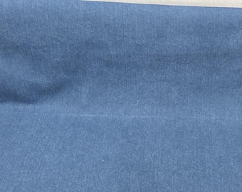 May include: A roll of blue fabric with a textured appearance. The fabric has a denim-like look and is folded over, revealing a white edge. The material appears to be soft and pliable, suitable for various textile projects.