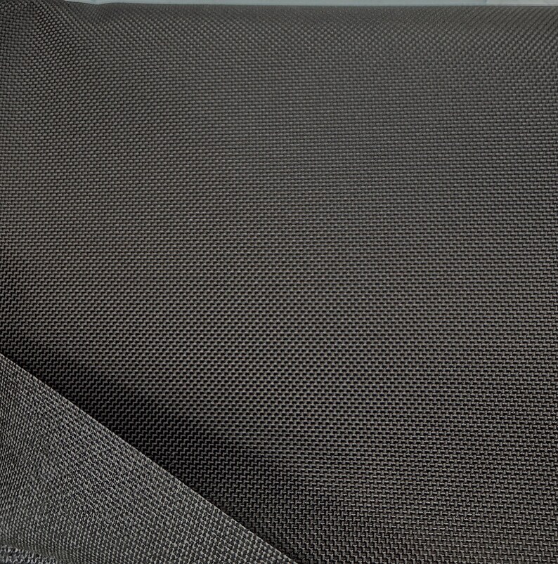 May include: Close-up of a dark gray fabric with a textured weave. The fabric has a subtle sheen and a smooth, even surface.