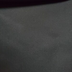 May include: A close-up of a black fabric with a smooth, slightly textured surface.
