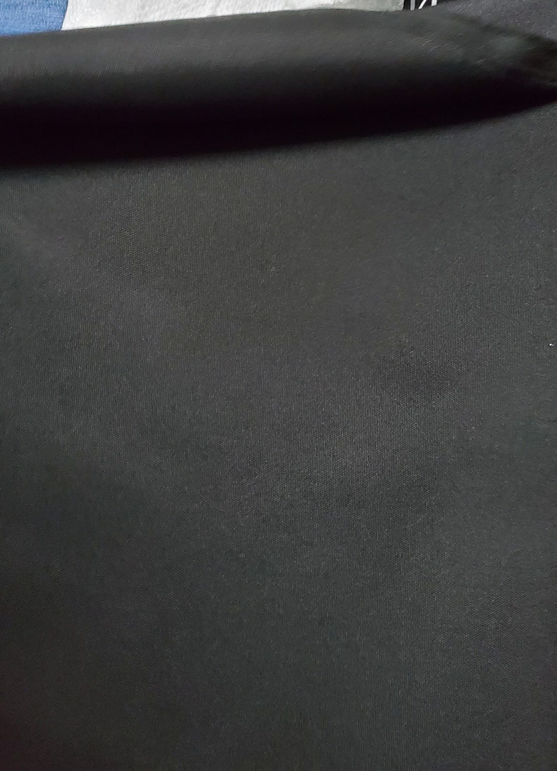 May include: A close-up of a black fabric with a smooth, slightly textured surface.