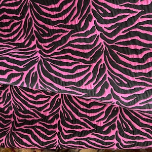 May include: Pink fabric with a black zebra print pattern.