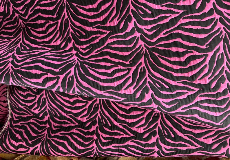 May include: Pink fabric with a black zebra print pattern.