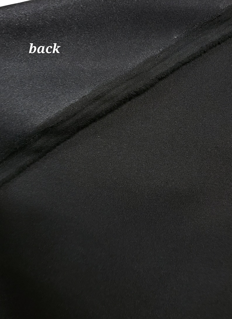 May include: Close-up of black fabric with a smooth, shiny texture on one side and a textured, woven texture on the other side. The word "back" is written on the smooth side.
