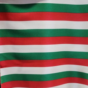 May include: Red, white, and green striped fabric. The fabric has a smooth, shiny texture.