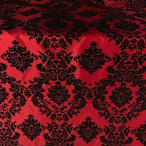 May include: Red fabric with a black damask pattern. The fabric has a satin-like sheen.