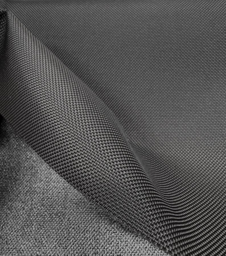 May include: Close-up of a dark gray fabric with a textured weave. The fabric is folded over itself, showing the underside of the material.