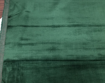 May include: A close-up of a dark green fabric with a subtle ribbed texture. The fabric is folded in thirds, showing the smooth, velvety surface.