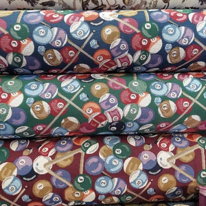 May include: Three fabric rolls with a repeating pattern of billiard balls and crossed cues. The top roll is blue, the middle roll is green, and the bottom roll is maroon.