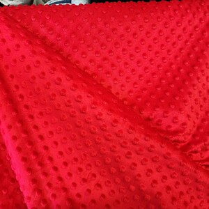 K&ouml;nnte beinhalten: Roter Minky-Stoff mit einem strukturierten Punktmuster. Der Stoff ist weich und pl&uuml;schig.