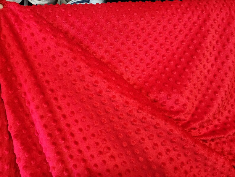 K&ouml;nnte beinhalten: Roter Minky-Stoff mit einem strukturierten Punktmuster. Der Stoff ist weich und pl&uuml;schig.