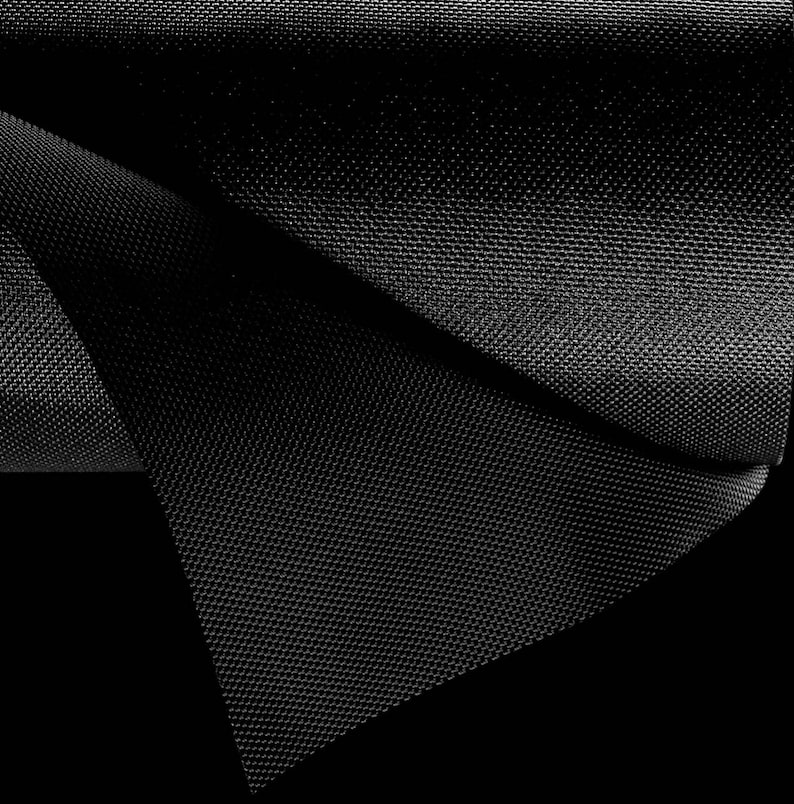 May include: Black fabric with a textured, woven pattern. The fabric is folded over on itself, creating a triangular shape.