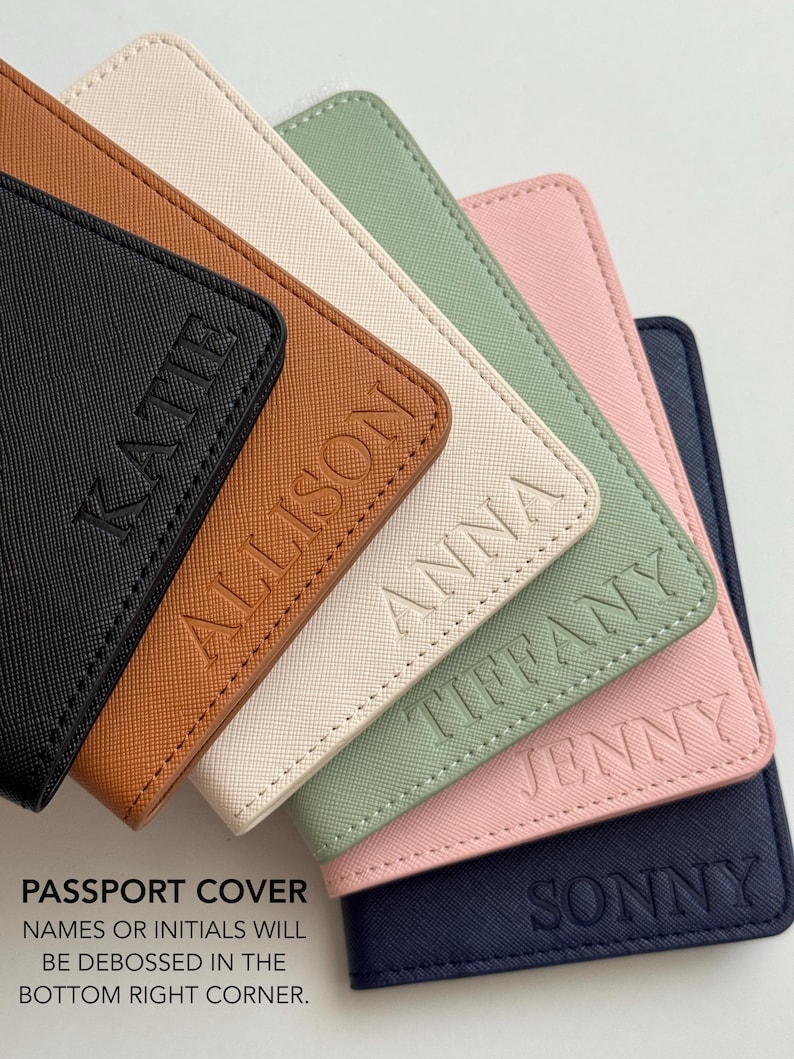 May include: A collection of six rectangular passport covers in black, tan, cream, sage green, light pink, and navy blue. Each cover features a textured surface and a debossed name in the bottom right corner: Katie, Allison, Anna, Tiffany, Jenny, and Sonny.