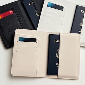 May include: A collection of passport holders in various colors, including black, white, and beige. Each holder features slots for cards and a passport. One holder is open, displaying a blue passport and a credit card.