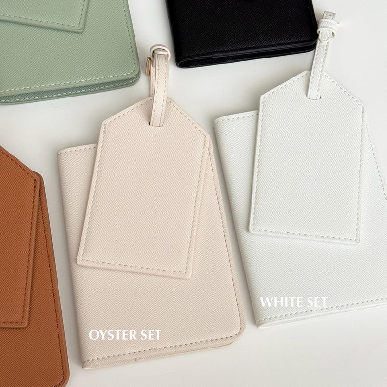 May include: A collection of passport holders and luggage tags in various colors. The image shows a light brown, light green, black, and white set. The "OYSTER SET" is labeled on the light brown set, and the "WHITE SET" is labeled on the white set.