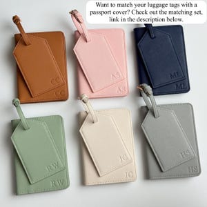 May include: A collection of six passport covers and luggage tags in various colors: brown, pink, navy, green, cream, and gray. Each set includes a passport cover and a matching luggage tag, with initials embossed on both items.