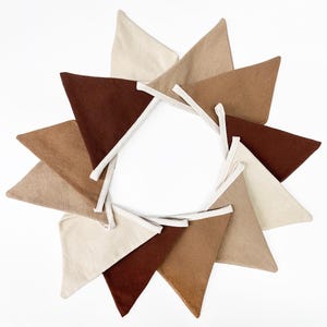 May include: A brown, beige, and cream felt pennant banner with white trim. The pennants are arranged in a circle.