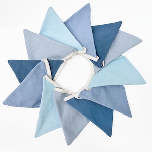 May include: A garland of ten blue and light blue fabric triangle flags with white trim. The flags are arranged in a circle.