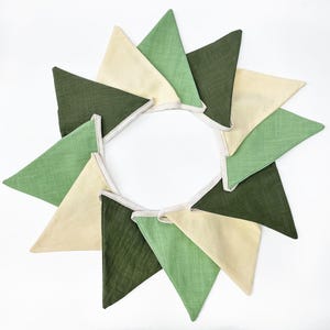May include: A garland of fabric triangles in shades of green and cream. The triangles are sewn together to form a continuous loop.