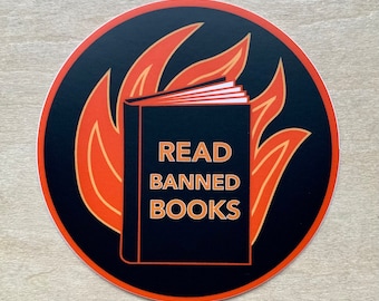 May include: A black and orange round sticker with a book on fire. The book has the text "READ BANNED BOOKS" on the cover.