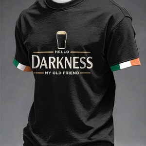 May include: Black t-shirt with the text "HELLO DARKNESS MY OLD FRIEND" in white and gold lettering. The shirt features a graphic of a pint of beer above the word "DARKNESS". The sleeves have green, white, and orange trim.