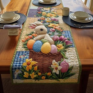 Könnte beinhalten: Gesteppter Ostern-Tischläufer mit einem Hasen, einem Korb, Eiern und Blumen. Der Läufer hat ein Patchwork-Design mit blauen, grünen und gelben Akzenten. Der Läufer liegt auf einem Holztisch. Ca. 150 cm lang.