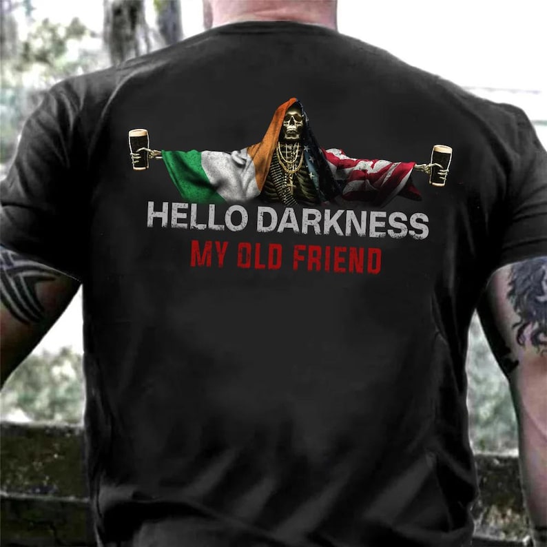 May include: Black t-shirt featuring a skeleton with flags of Ireland and the United Kingdom, holding beer mugs. The shirt has the text "HELLO DARKNESS MY OLD FRIEND" in white and red lettering. The design is a humorous take on a classic theme.