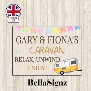 May include: Wooden sign featuring the text "GARY & FIONA'S CARAVAN" and the phrases "RELAX, UNWIND, ENJOY!". A yellow and white caravan illustration is on the right. The sign has a banner of colorful flags at the top and a "Made in UK" sticker.