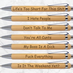 May include: Seven bamboo pens with silver-coloured metalwork, each engraved with a different phrase. The phrases include "Life's Too Short For This Shit," "I Hate People," and "Is It The Weekend Yet?" These pens are designed for writing.