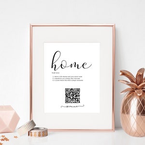 Op de afbeelding: Een ingelijst afdruk met het woord "home" in cursief schrift en een definitie van het woord. De afdruk bevat ook een zwart-witte QR-code met het woord "scan me" eronder.