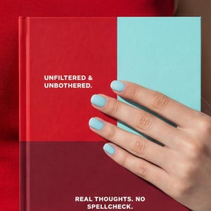Puede incluir: Un diario de tapa dura con una cubierta roja y turquesa. El diario tiene el texto "UNFILTERED & UNBOTHERED" y "REAL THOUGHTS. NO SPELLCHECK." Una mano con esmalte de uñas azul claro sostiene el diario.