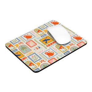 Puede incluir: Alfombrilla de ratón rectangular con un diseño colorido y estampado con monos naranjas, tucanes y motivos tropicales. La alfombrilla tiene un borde negro y un ratón de ordenador blanco encima.